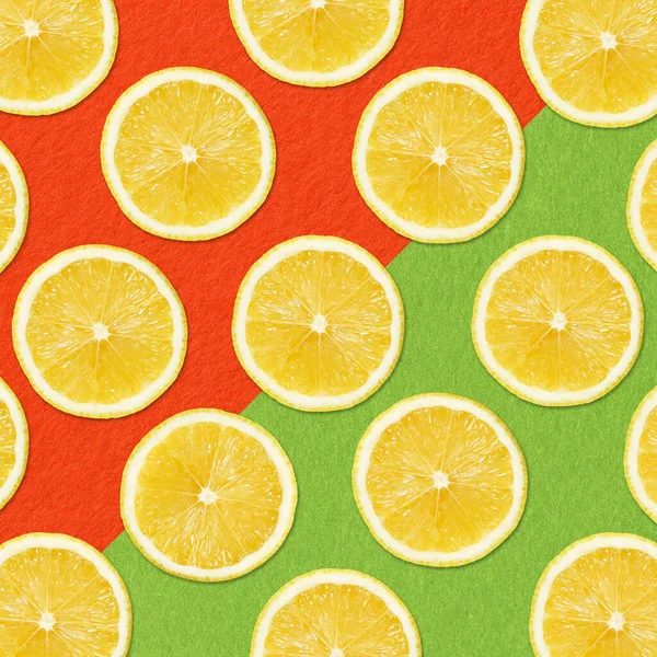 概要柑橘類の背景 赤と緑の背景に黄色のレモンスライス — ストック写真
