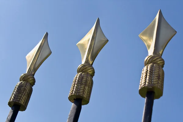 Golden spikes on iron fence over blue sky — Stock Photo, Image