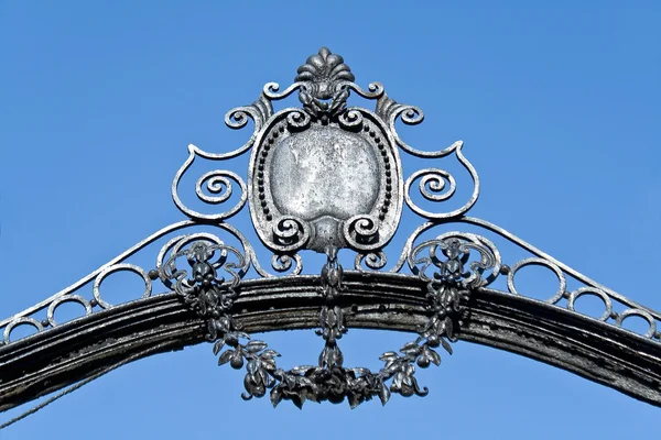Арка на старых железных воротах над голубым небом — стоковое фото