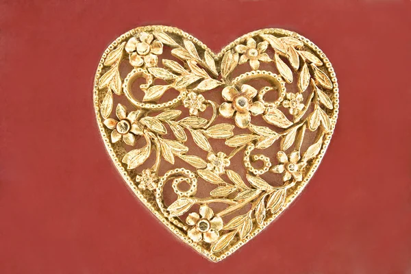 Golden heart jewelry on red background — Stock Photo, Image