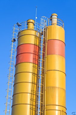 Mavi gökyüzü üzerinde sarı beton siloları