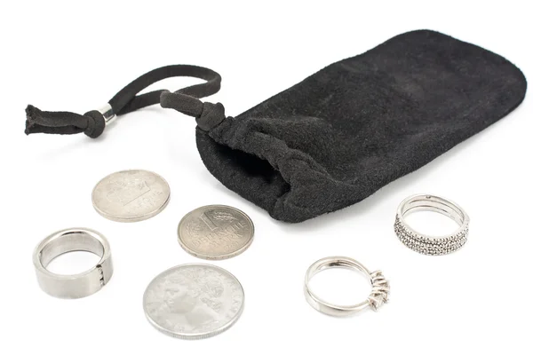 Bolso de terciopelo negro con anillos y monedas de plata en blanco — Foto de Stock