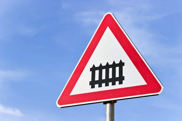 Railroad crossing sign with a barrier over blue sky — Stock Photo, Image