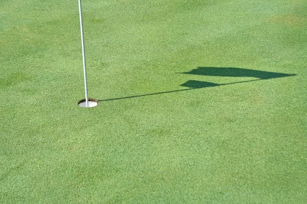 Hole and shadow of golf flag waving — Stock Photo, Image