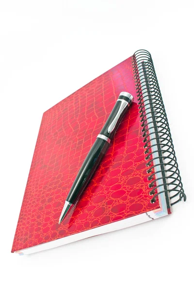 Stift auf rotem Spiralheft isoliert auf weißem Papier lizenzfreie Stockbilder