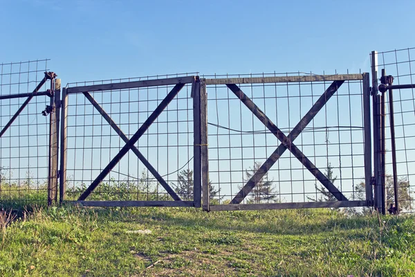 Stare drewniane metalowe ogrodzenie i trawa zielona z błękitnego nieba — Zdjęcie stockowe