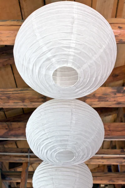 Three white paper lanterns (lampoons) on wooden ceiling — Stock Photo, Image