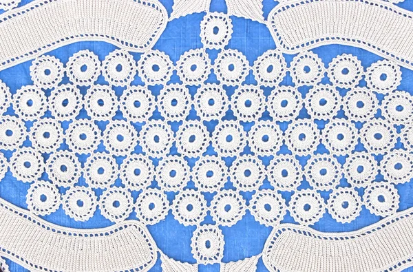 Handmade white lace on blue background — Stock Photo, Image