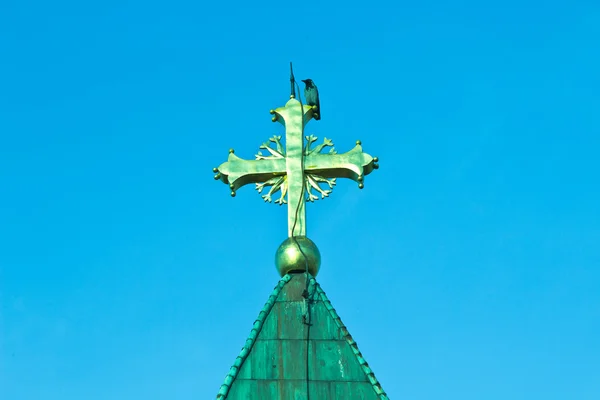 Rabe am goldenen Kreuz auf der Kirche über dem Himmel — Stockfoto