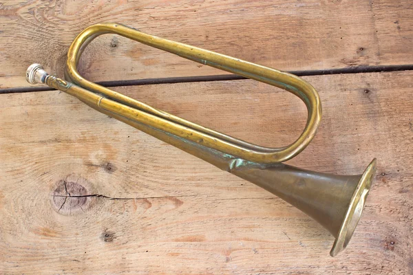 Old broken army trumpet on wooden background — Stock Photo, Image