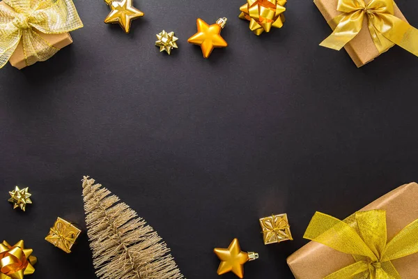 Concetto natalizio. Regali con fiocchi d'oro, stelle e un abete su uno sfondo nero. Capodanno. Layout piatto, vista dall'alto, spazio di copia — Foto Stock