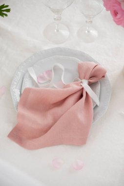 Beyaz tabakta zarif pembe keten peçete, düğün konsepti, seçici odaklı resim
