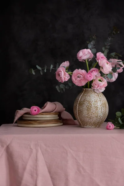 ピンクのテーブルクロスと暗い壁にピンクのRanunculus花 選択的な焦点画像 — ストック写真
