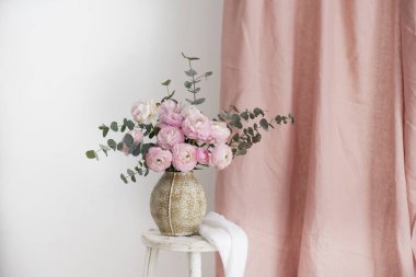 Bej bir vazoda bir buket şakayık ve ranunculus, seçici odak resmi.