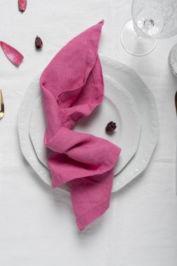 Masa dekorasyonu kavramı, beyaz tabak üzerindeki pembe keten peçete, seçici odak resmi