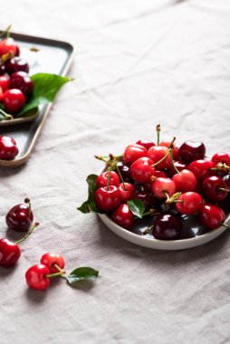 Keten masa örtüsünde yeşil yapraklı taze kiraz, seçici odak resmi