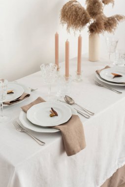 Concept of table decoration with linen white tablecloth and beige napkins, selective focus image