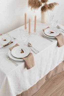 Concept of table decoration with linen white tablecloth and beige napkins, selective focus image