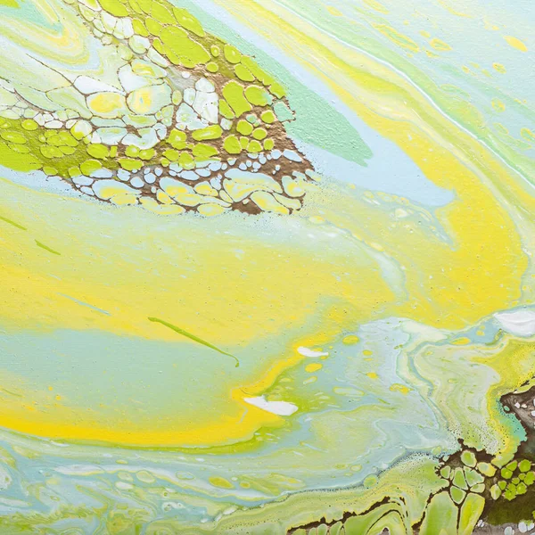 Fluid acrylic painting in green and yellow colors, selective focus image