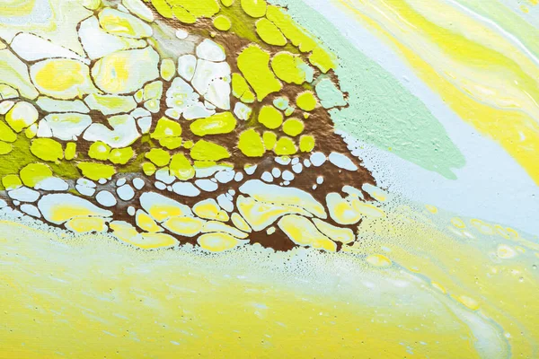 Fluid acrylic painting in green and yellow colors, selective focus image