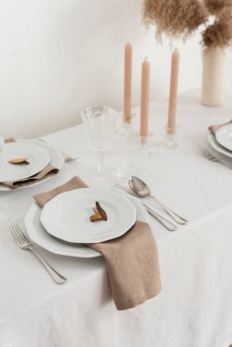 Concept of table decoration with linen white tablecloth and beige napkins, selective focus image