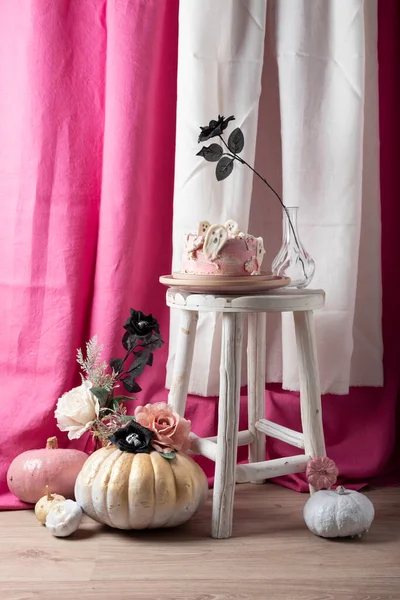 Halloween party decoration with pink cake and colored pumpkins, selective focus image