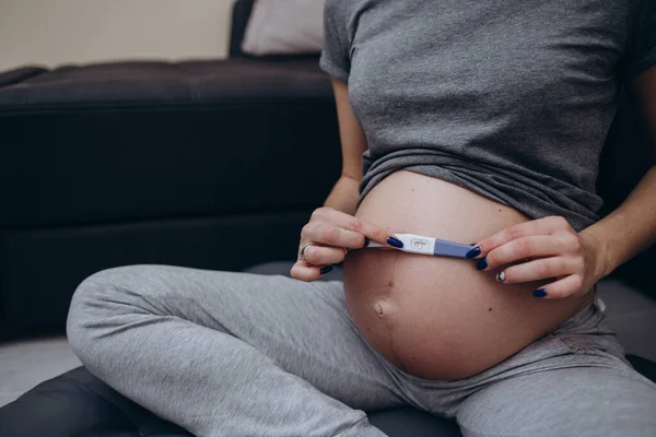 The concept of a pregnant woman holding a pregnancy test and remembering how she first learned about pregnancy