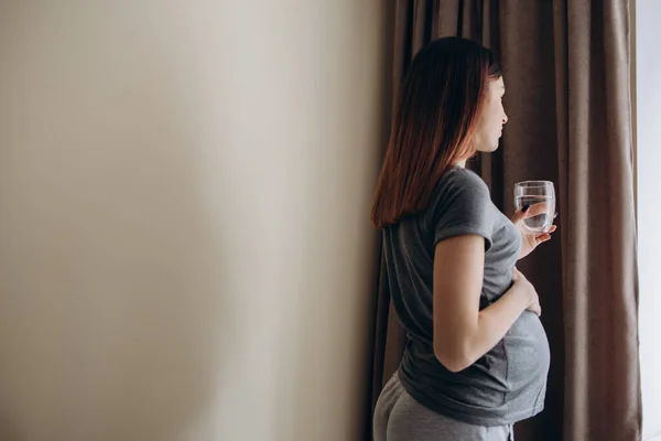 Hidratación Positivo Embarazada Chica Beber Agua Vidrio Pie Mirando Ventana — Foto de Stock