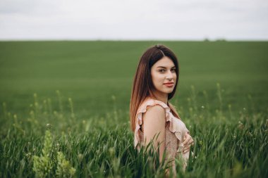 güzel kızın rahatlatıcı yeşil sahada otururken