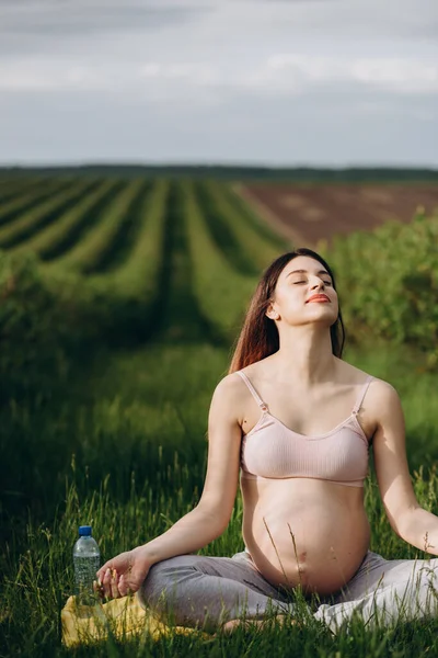 Hermosa Embarazada Haciendo Yoga Sentada Campo Verde Vestido Con Pantalones — Foto de Stock