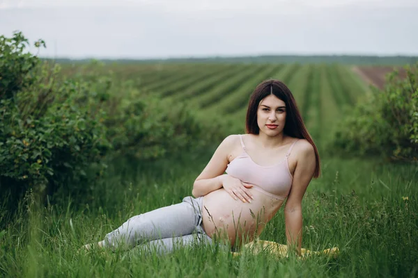 日当たりの良い夏の日に草の上フィットネス運動をして妊娠中の女性 — ストック写真
