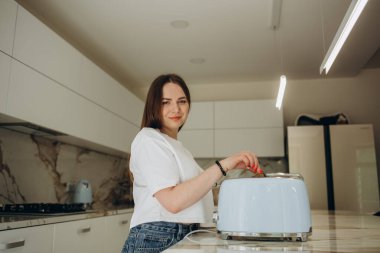 Mutfaktaki masada tost makinesi kullanan genç bir kadın..