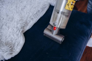 Modern kablosuz elektrikli süpürgeyle kanepeyi temizleyen kadın. Özel bir hortumu var. Yakın plan. Kablosuz elektrik süpürgesi ile kuru temizleme kavramı
