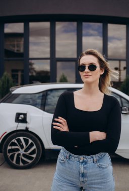 Elektrikli benzin istasyonunda kadın elektro arabayı şarj ediyor.