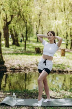 Genç atletik kadın dışarıda boylamsal bölünmeler yapıyor. Kız spora gidiyor, sağlıklı yaşam tarzı, atletik vücut. Spor kıyafetleri, siyah bluzu ve şortu var. Spor konsepti.