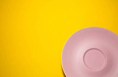 Sarı arka planda boş pembe bir tabak. Minimalizm.