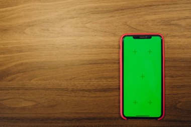 Akıllı telefonun eski ahşap zeminde yeşil bir ekranı var..