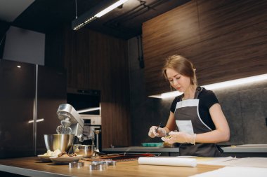 Şekerlemeci orijinal dikdörtgen kesim kullanarak zencefilli kurabiye yapar. Koruyucu eldivenli kadın elleri. Yuvarlak hamurlu. Özel şekilli kalıplar.