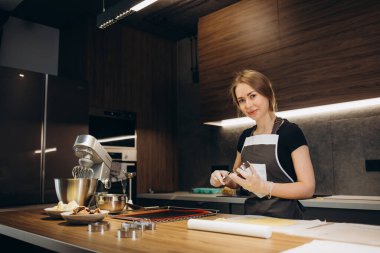 Genç bayan pasta şefi bir kalıba sıvı krema döküyor. Pasta hazırlama, profesyonel bir mutfakta tatlı..