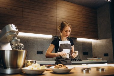 Şekerlemeci orijinal dikdörtgen kesim kullanarak zencefilli kurabiye yapar. Koruyucu eldivenli kadın elleri. Yuvarlak hamurlu. Özel şekilli kalıplar.