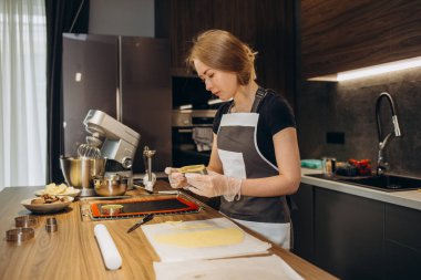 Şekerlemeci orijinal dikdörtgen kesim kullanarak zencefilli kurabiye yapar. Koruyucu eldivenli kadın elleri. Yuvarlak hamurlu. Özel şekilli kalıplar.