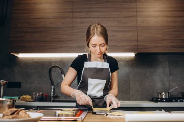 Güzel kadın pastacı modern mutfakta hamura bakarak tatlı hazırlıyor.