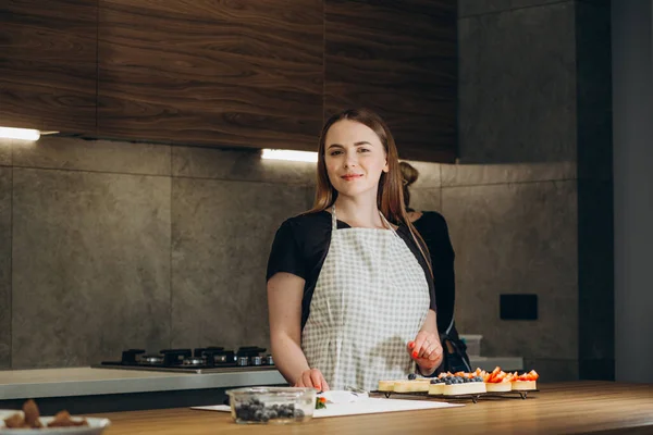 Pastry chef in the kitchen decorating a cake of chocolate,fruit,candies,Confectioner is decorating chocolate cake,cooking class, culinary, bakery, food and people concept