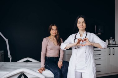 Gülümseyen genç Hintli bayan kardiyolog kalp sembolünü parmaklarıyla gösteriyor, hastalara sevgisini ve desteğini ifade ediyor, sağlık hizmetleri bağış konsepti.