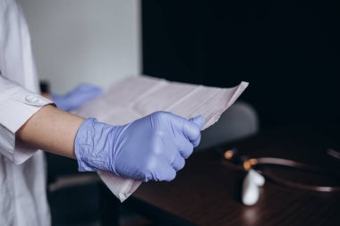 Bir doktorun ellerinde kalp kardiyogramı. Kardiyolog bir elektrokardiyografın tanıklığını inceliyor..