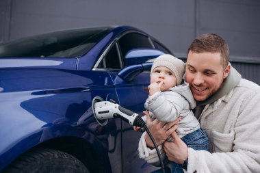 Baba kızıyla oynarken elektrikli arabayı şarj ediyor.