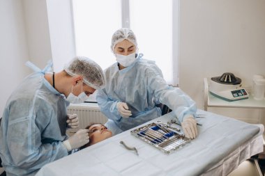 Konsantre cerrahi ekibi ameliyathanede bir hastayı ameliyat ediyor. Karmaşık makinelerle yıllarca eğitim almış iyi eğitimli bir anestezi uzmanı ameliyat boyunca hastayı takip eder..