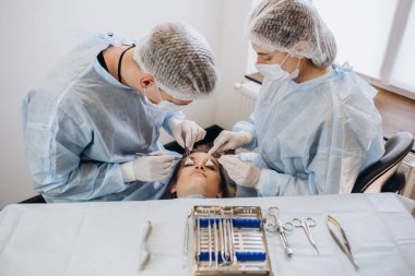 Konsantre cerrahi ekibi ameliyathanede bir hastayı ameliyat ediyor. Karmaşık makinelerle yıllarca eğitim almış iyi eğitimli bir anestezi uzmanı ameliyat boyunca hastayı takip eder..