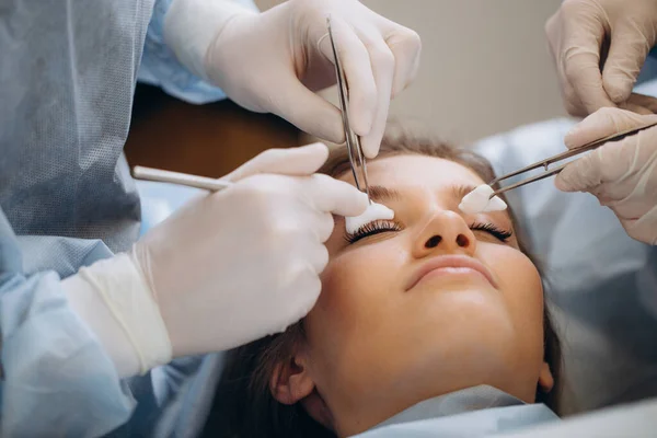 Surgeon and his assistant performing cosmetic surgery on nose in hospital operating room. Nose reshaping, augmentation. Rhinoplasty.