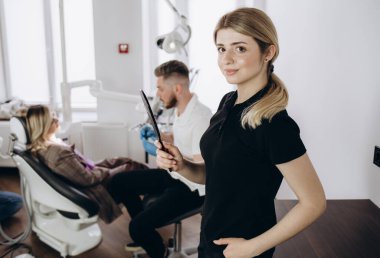 Diş Hekimliği çalışma arka plan ile gülümseyen bir dişçide asistan portresi
